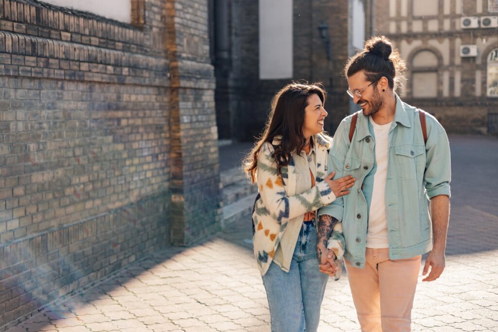 Hipster couple holding hands and talking a walk on street at old town.